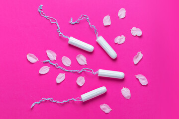 Fototapeta na wymiar Female tampons with with cherry petals on a pink background. Hygienic white tampon for women. Cotton swab.