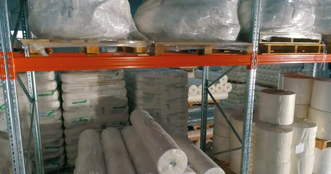 Flight to the warehouse of non-woven fabrics. Warehouse at the nonwovens factory. Large modern warehouse with synthetic winterizer rolls