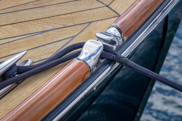 Navy Rope Running Through Chrome Fairlead Onto Teak Deck of Yacht