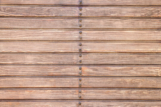Background of brown wooden slats with screws in the center.