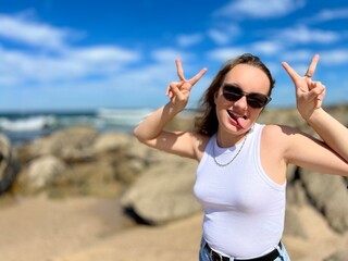 a girl on a sea in a white blouse, fair-haired, shows different cheerful emotions, she makes faces,...