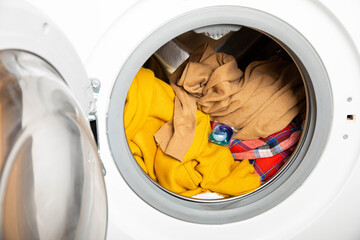  laundry detergent capsule into washing machine indoors, closeup.Colorful laundry eco gel in capsule. Washing clothers.The concept of washing and cleanliness