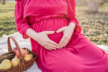 Heart shaped hands on the belly of the pregnant lady