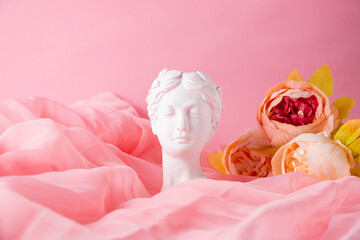 Bust of a Greek goddess on a pastel pink background. Minimal flat still life. Beauty overhead concept.