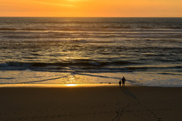 Panoramic photo of a father and son on the beach looking at the sunset