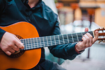 Street musician. A man plays the guitar on a city street. Close up photo.