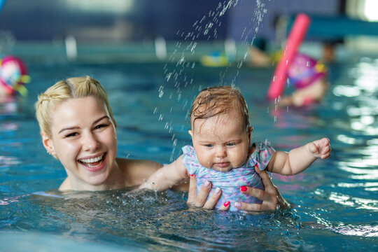 Young beautiful blonde mother with baby in pool. Concept of sport, training and family