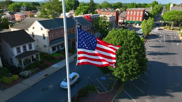 USA flag at half mast. Nation grieves and mourns tragedy in America. Small town scene with Pennsylvania flag.