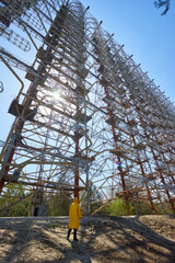 young man in yellow protective suit standing near military secret object antenna radar Duga in...
