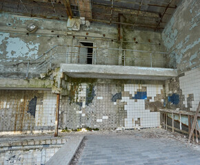 Abandoned swimming pool in Pripyat. Destroyed gym in a radioactive city. The street is overgrown with trees and bushes.