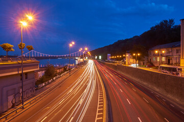 Fototapeta premium KYIV, UKRAINE, September 04, 2017: Embankment highway with tight traffic, pensot bridge in the background, evening photo