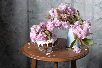Easter cake and painted eggs and a bouquet of pink sakura flowers on a table