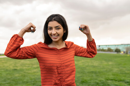Beautiful strong Indian woman showing muscles outdoors in the park. girl power concept