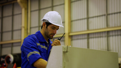Technical man talking on radio or walkie talkie while working at industrial plant or factory