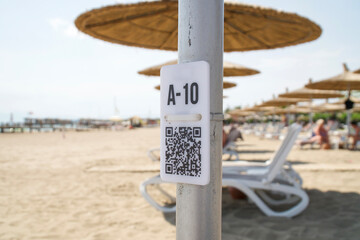 QR code on the pole on blurred beach. QR code with seat number A - 10 for select menu