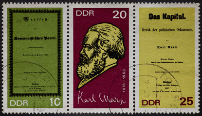 a postage stamp from GERMANY, DDR, showing a portrait of the philosopher and political economist Karl Marx. With Manifestos of the Communist Party and Das Kapital. Circa 1968