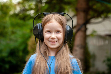 One single happy cheerful school age child, girl wearing large headphones listening to music...