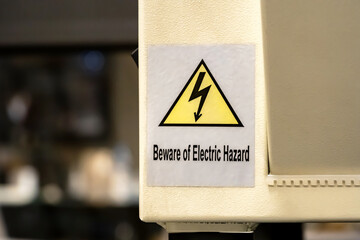Beware of electric hazard sticker warning label on a generic industrial factory production line...