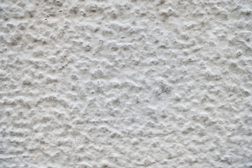 Rough and light plaster of a facade with a coarse structure and slight cracks