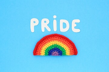 Crochet rainbow and Pride lettering on blue background. LGBT color flag gay pride community, equal...