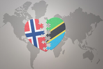 Obraz premium puzzle heart with the national flag of norway and tanzania on a world map background. Concept.