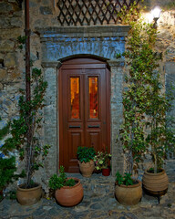 Fototapeta na wymiar Night view of a house entrance, wood and glass door. Mesta town, Chios island, Greece.