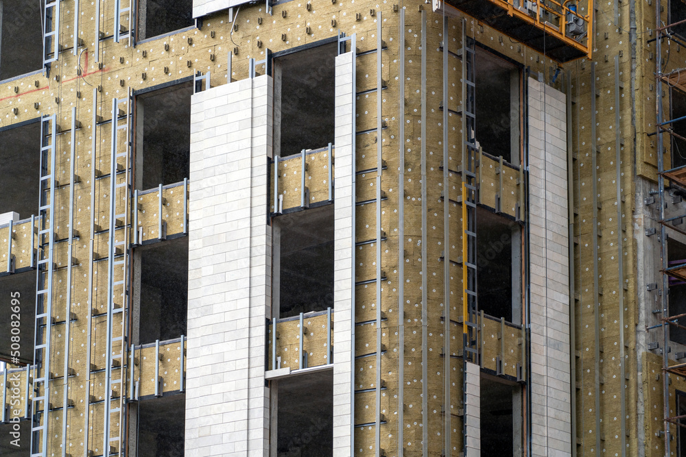 Poster monolithic concrete frame of apartment building under construction with partially attached facade cl
