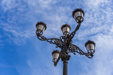 Fototapeta na wymiar Ozdobna latarnia uliczna na tle niebieskiego nieba. 