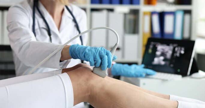 Doctor conducts ultrasound examination of patient knee in clinic