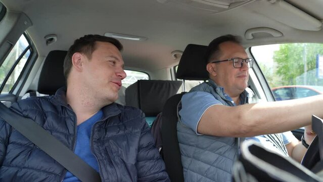 Friends looking map on cell phone in car road trip concept. Two business men together in car on business trip or in carpool