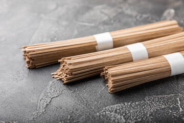 Buckwheat paste on a black cement background. Raw noodles. Ingredients for a gluten-free dish. Dried buckwheat soba noodles. Traditional Japanese food. Healthy food. Place to copy.
