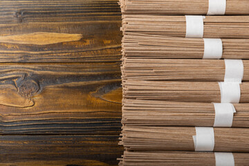 Buckwheat pasta on brown texture wood background. Raw noodles. Ingredients for a gluten free dish....