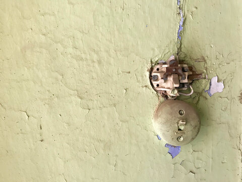 Surface-mounted electrical switch on a worn and outdated painted wall