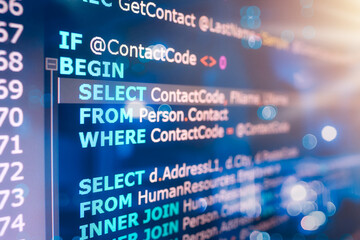 SQL (Structured Query Language) code on computer monitor and server room background. Example of SQL...