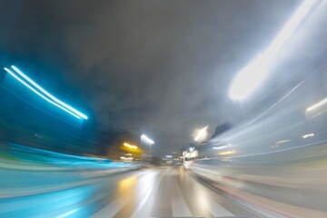 CITY STREET AT NIGHT WITH MOTION BLURRED LIGHTS OF FAST MOVING CARS, MODERN CITYSCAPE, RUSH ON THE STREET. High quality photo