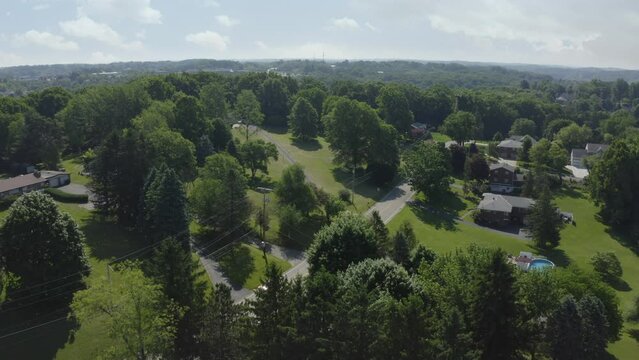 A forward moving aerial summer establishing shot of a typical upscale Pennsylvania residential neighborhood. Pittsburgh suburbs. Alternate angles available.  	