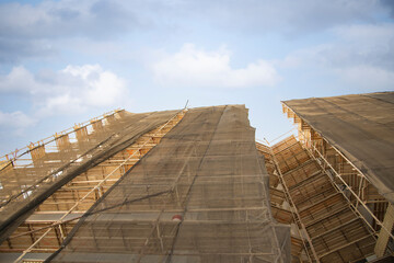 Construction site with a protective safety net on the facade of a building with scaffolding. Old housing renovation concept. Concept of success, growth, direction. An arrow marks the path. High