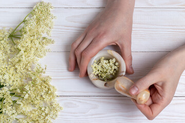 Mortar and pestle with elder flowers. Phytotherapy and herbal medicine concept.