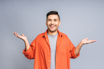 Look over there! Happy young handsome man in casual pointing away at copyspace and smiling while standing isolated over white grey background.