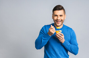 Happy Young ukrainian Handsome Man eating Yogurt isolated over grey white Background. Healthy lifestyle concept.