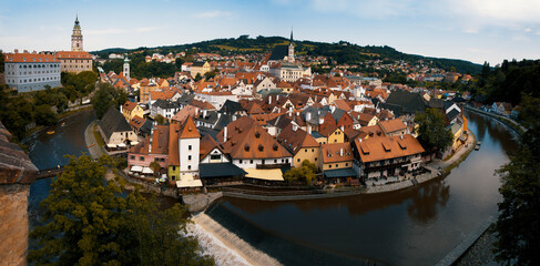 Naklejka na ściany i meble Panoramatic view of the town of Cesky Krumlov, castle, St. Vitus church and Vltava river from the castle. Colorful picturesque old town houses. Český Krumlov, South Bohemia, Czech Republic.