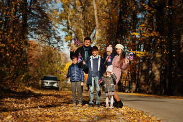 National holiday of United Kingdom. Large family with four kids holding british flags in autumn...