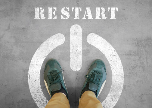 RESTART と書かれたコンクリートの地面と自分の足