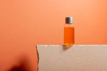 A bottle of serum and essential cosmetic oil on a podium with shadows in the background. Spa product for skin care
