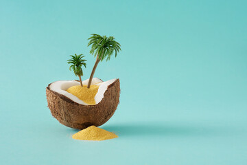 Creative layout made of coconut, color sand and palm trees on blue background. Tropical beach...