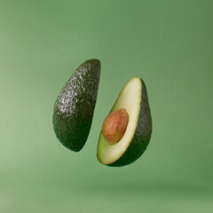 Avocado sliced ​​on green color background. Minimal fruit concept.