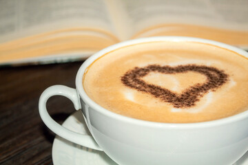 Coffee drink near the book. Coffee up close. Heart in coffee