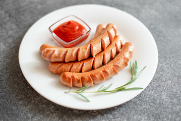 grilled sausages on a white plate on a stone background 