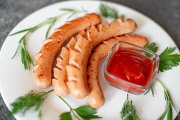 grilled sausages on a white plate on a stone background 