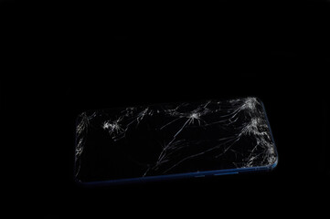 smartphone with a broken screen lies horizontally on a black background